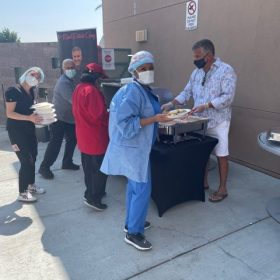 People serving food outdoors together.