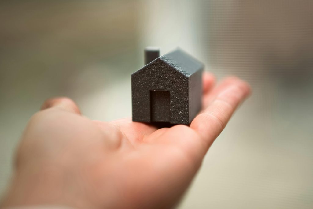 Hand holding a small house model.