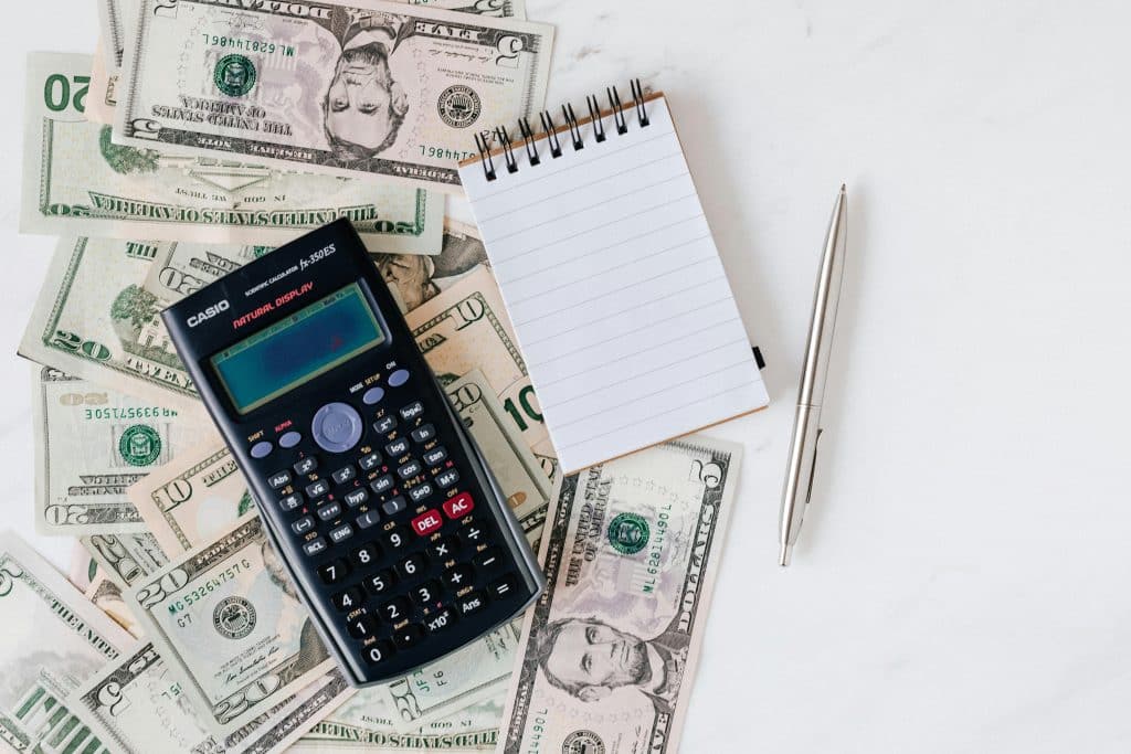 Calculator, cash, notebook, and pen.